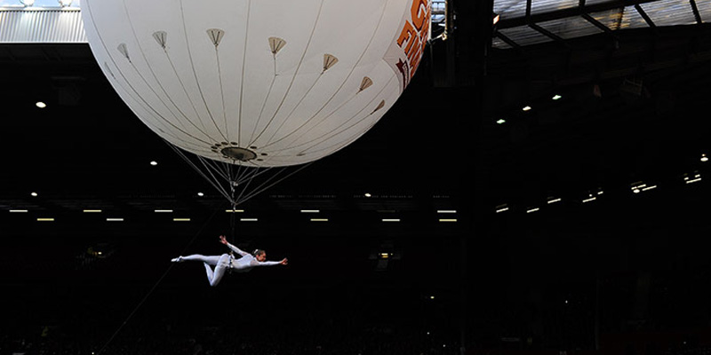 A photo of an aerial performer suspended from a large floating balloon at Old Trafford football stadium, Manchester, prior to the Rugby League Super League Final 2012